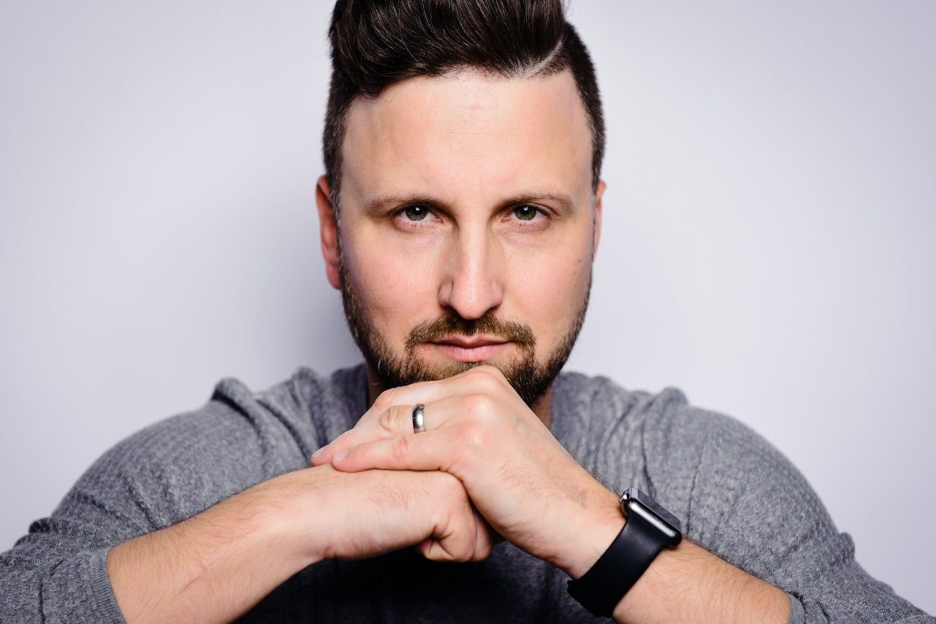 A woman with curly hair and glasses claps, sitting among a group of people at a coaching event run by Silent Warrior